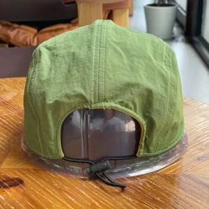 Green quick-dry cap detail, lightweight outdoor hat with contrast stitching and cord.