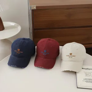 Primo piano dettagliato di tre cappellini da baseball colorati con ricamo di orsetto.