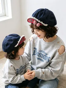 Detailed shot of children's denim beret with cute red plaid bows and delicate lace trim.