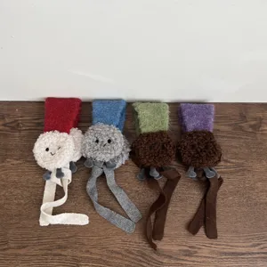 Gedetailleerd overzicht van winter lamswollen oorklappers voor kinderen met gezichtje en lange linten.