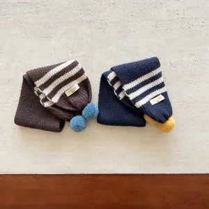 Dettaglio in primo piano della sciarpa invernale a righe per bambini con pon-pon, calda e morbida.