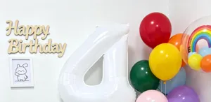 Detail shot of white 40-inch number 4 foil balloon with colorful birthday party balloons setup.