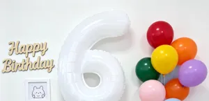 Detail view of large white number 6 foil balloon with colorful birthday party balloons.