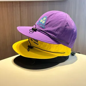 Close-up detail of stacked quick-dry children camp caps with embroidery and drawstring.