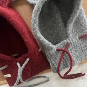 Detalle de pasamontañas de punto suave, diseño bicolor con orejas lindas y cordones ajustables.