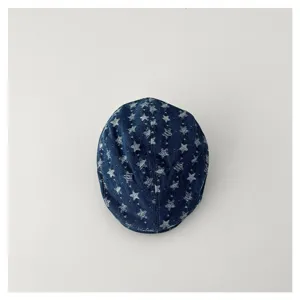 Détail en gros plan de la casquette plate en denim lavé pour enfant avec imprimé étoiles.