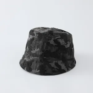 Vue détaillée du bob camouflage usé montrant une texture de tissu rétro et un délavage sombre.