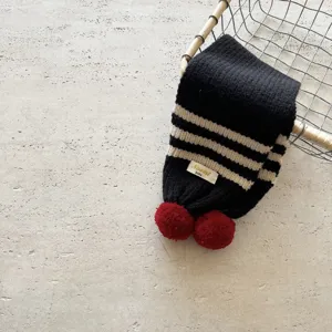 Dettaglio sciarpa in maglia per bambini a righe bianco nero pon pon rossi collo invernale caldo