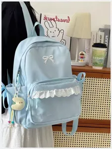 Primo piano dettaglio dello zaino azzurro chiaro con fiocco bianco e tasca con volant.
