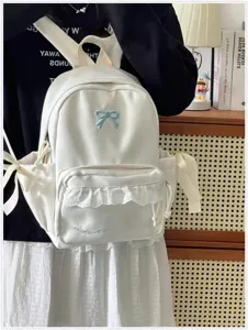 Dettaglio dello zaino bianco stile coreano con fiocco blu e graziosa tasca frontale con volant.