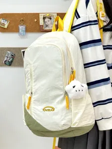 Detalle de una mochila casual de lona en blanco y verde con un lindo colgante.