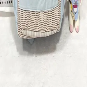 Primo piano dettaglio dello zaino scolastico blu carino con tasca a righe e peluche.