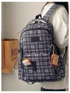 Detail view of retro plaid school backpack, casual daily canvas shoulder bag with cute charms.