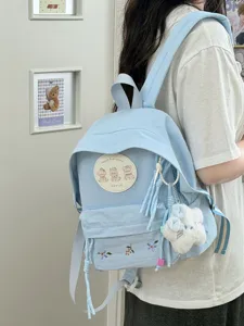 Mochila azul clara de estilo japonés con parches de ositos y bordado floral para uso diario.