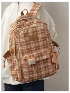 Detailed view of brown plaid school backpack with cute toast pendants and leather label patch.