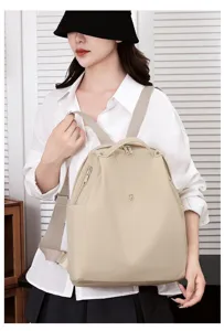 Detail view of the lightweight beige nylon backpack with adjustable straps and multiple pockets.