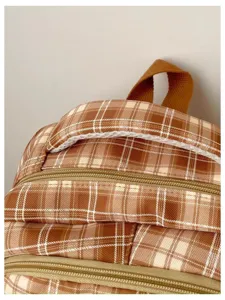 Brown plaid backpack detail, retro school bag close-up, durable zipper and top handle design.