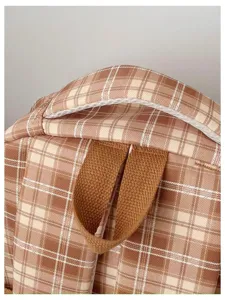 Close-up detail of vintage plaid backpack top handle and strap connection part.