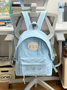 Mochila escolar de lona azul claro con insignia de oso lindo y bordado floral para estudiantes.