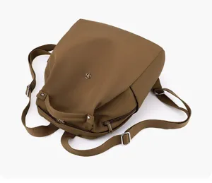 Detail view of the lightweight nylon backpack in brown, featuring durable straps and zippers.
