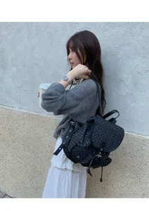 Detail view of polka dot backpack in daily street scene, showcasing design and strap.