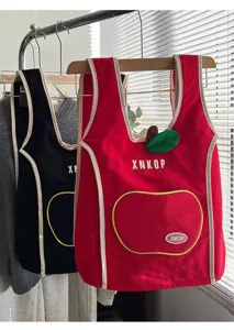Vista detallada de mochila de lona con forma de manzana en rojo y negro con bolsillo delantero.