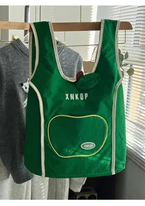 Detalle de mochila chaleco manzana verde, diseño tinto con ribete blanco, bolso casual de lona.
