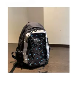 Detailed view of the contrast color school backpack with blue hearts and front bungee cord design.