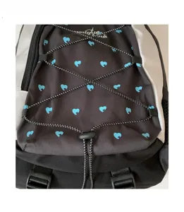 Close-up view of the black backpack front with blue heart pattern and bungee cord detail.