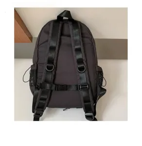 Detailed view of the black backpack back showing adjustable straps, chest buckle and mesh pockets.