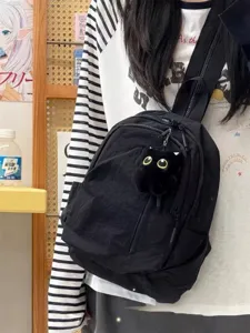 Small black nylon backpack detail view, casual daypack with cute cat plush charm for daily travel.