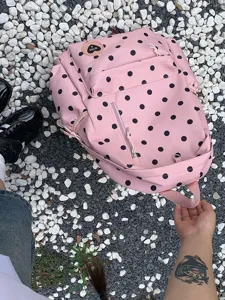 Vista dettagliata di un grazioso zaino rosa a pois neri, con tasca anteriore e spallacci resistenti.