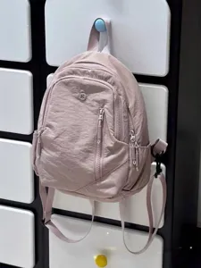 Casual pink nylon backpack with front zip pocket, lightweight travel daypack for women.