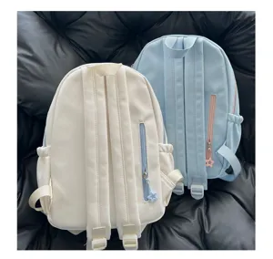 Vue détaillée de sacs à dos en toile blanc et bleu, montrant les bretelles et poches zippées au dos.