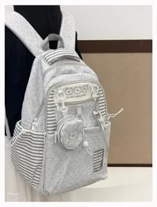 Close-up view of grey polka dot school backpack with cute bear print and striped pockets.