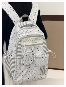 Detailed view of grey heart patterned school backpack with striped pockets and cute bear charm.