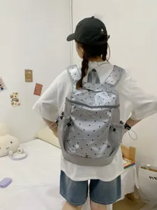 Close-up view of the grey Y2K style backpack with black dots and star details worn on model.