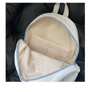 Vue de détail intérieure du sac à dos blanc ita bag, montrant plusieurs poches et zip bleu.
