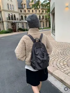 Detail view of casual nylon polka dot backpack worn outdoors, showing strap and pocket.