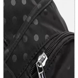 Close-up detail of black polka dot backpack showing fine zipper and durable fabric texture.