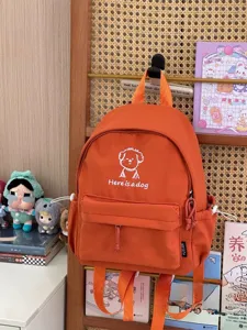 Orange canvas backpack detail showing cute dog print, front pocket, and casual daily style.