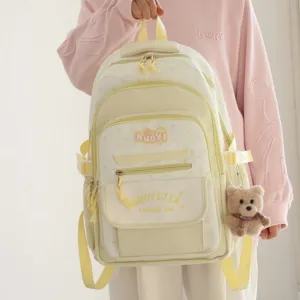 Vista dettagliata dello zaino scolastico giallo in stile giapponese con tasche e ciondolo orsetto.