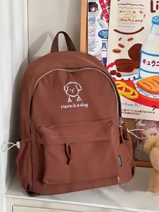 Detail view of the cute brown student backpack featuring white dog embroidery and front pocket.