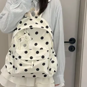 Close-up detail of the stylish white and black polka dot backpack with a cute pearl bow pendant.