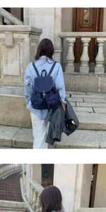 Detailed lifestyle shot of a navy blue polka dot backpack worn by a model outdoors.