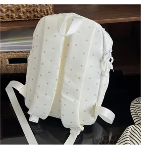 Detailed view of white polka dot backpack, lightweight student bag showcasing shoulder straps and fabric.