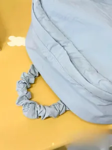 Close-up detail of light blue puffy backpack featuring trendy scrunchie gathered handle design.