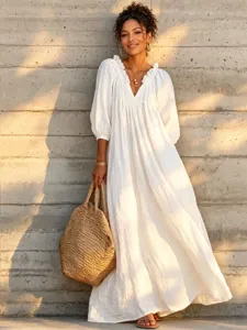 Detailed view of a white V-neck lantern sleeve maxi dress for boho beach vacation style.