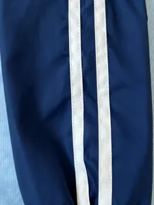 Close-up detail of men's sportswear sleeve featuring dual white stripes on navy blue fabric.
