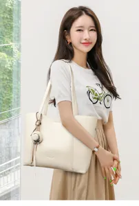 Gedetailleerd uitzicht op de elegante beige lederen tas met stijlvolle strooien hanger.